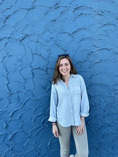 a bright, smiling Molly Ryan leaning against a blue wall